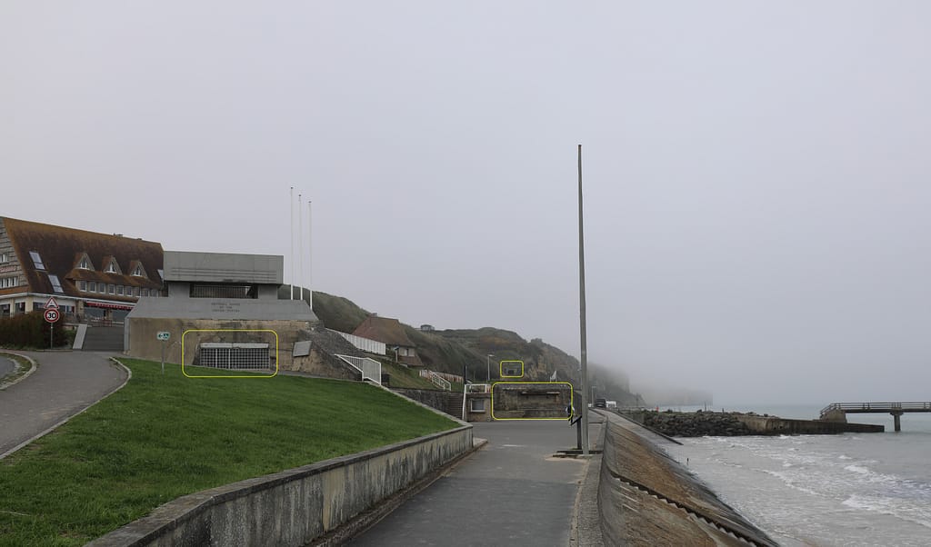 Example of the German bunker configuration. This is Vierville Draw/Dog One, the position depicted in the opening scene of 'Saving Private Ryan'. In this photo there are three bunkers visible: two WN72 bunkers in the foreground and one WN73 bunker on the cliff in the background. The embrasures are highlighted in yellow. All face along the beach, none face to sea.